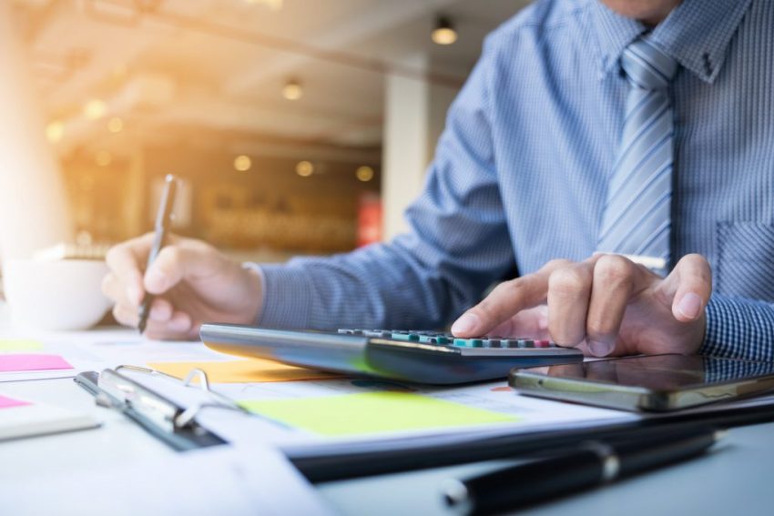 Agente inmobiliario calculando comisiones con calculadora en oficina